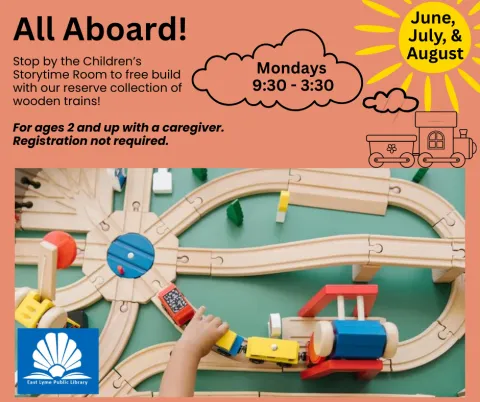 A child is driving a toy train on a wooden train track.