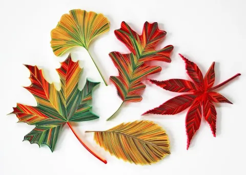 A variety of leave varieties in red, orange, green and yellow made by paper quilling. 