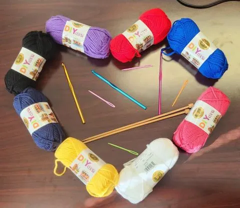 A heart made of yarn with knitting needles and crochet hooks inside it.