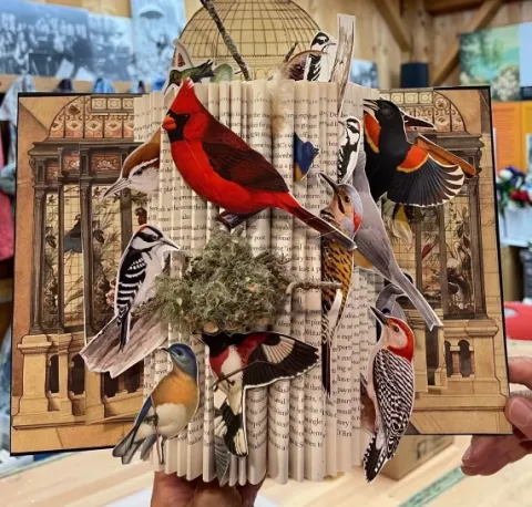 An image of an altered book from the Florence Griswold Museum with birds on it.
