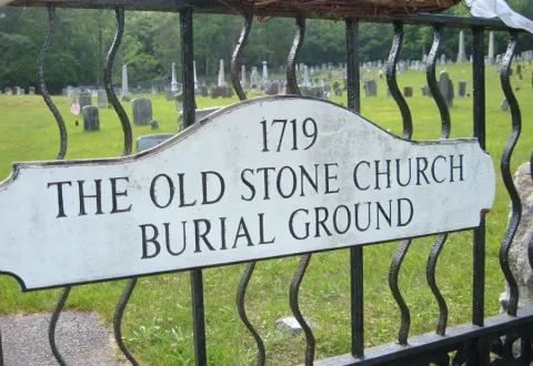 The sign on the Cemetery gate. It reads, "1719 The Old Stone Church Burial Ground" 