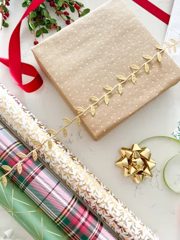 A photo of wrapping paper, a wrapped gift and a gold bow. 