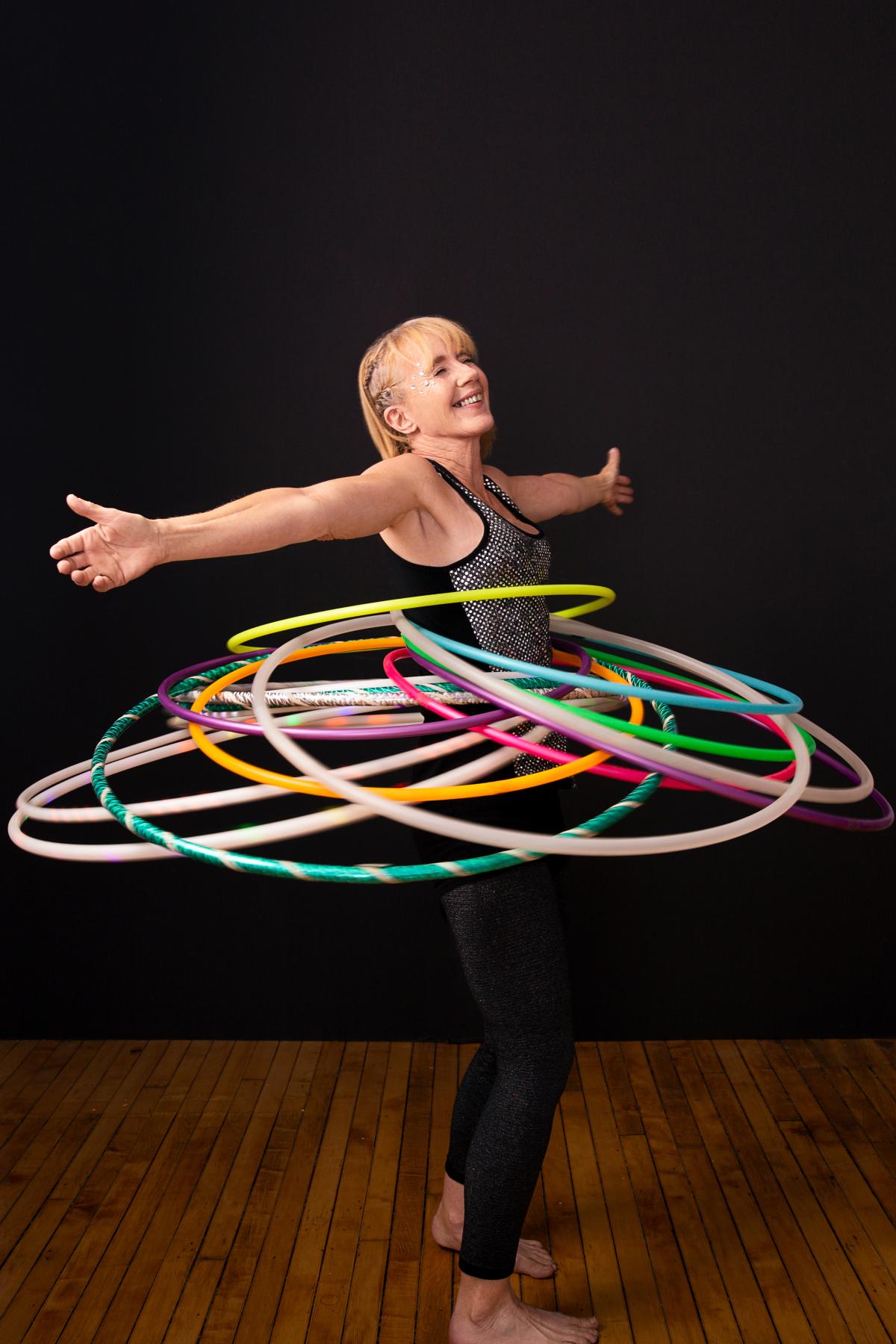 Hula Hoop artist Judi Jones is balancing and circling a dozen hula hoops at the same time. 