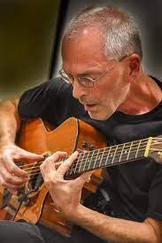 A photograph of the presenter Peter Biedermann with his guitar 